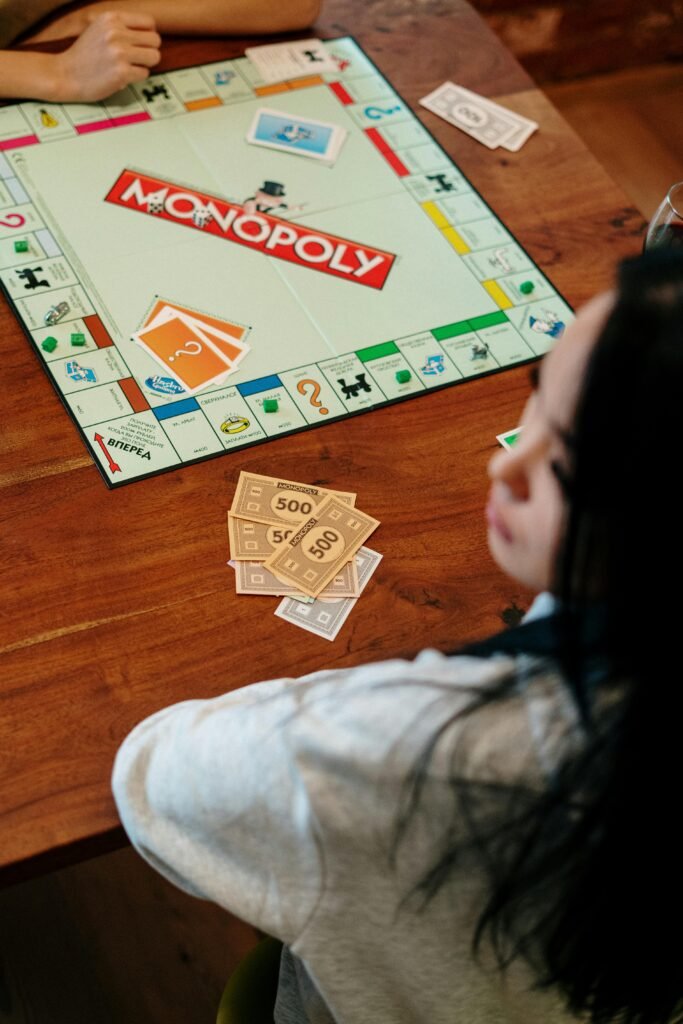 A group of adults playing Monopoly on a wooden tabletop, focused on strategy and fun.